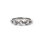 Crafted in 14KT white gold, this ring features 3 round brilliant-cut diamonds in a row, with a blue sapphire on either side on a vintage-inspired hand engraved band.