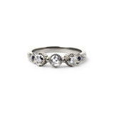 Crafted in 14KT white gold, this ring features 3 round brilliant-cut diamonds in a row, with a blue sapphire on either side on a vintage-inspired hand engraved band.