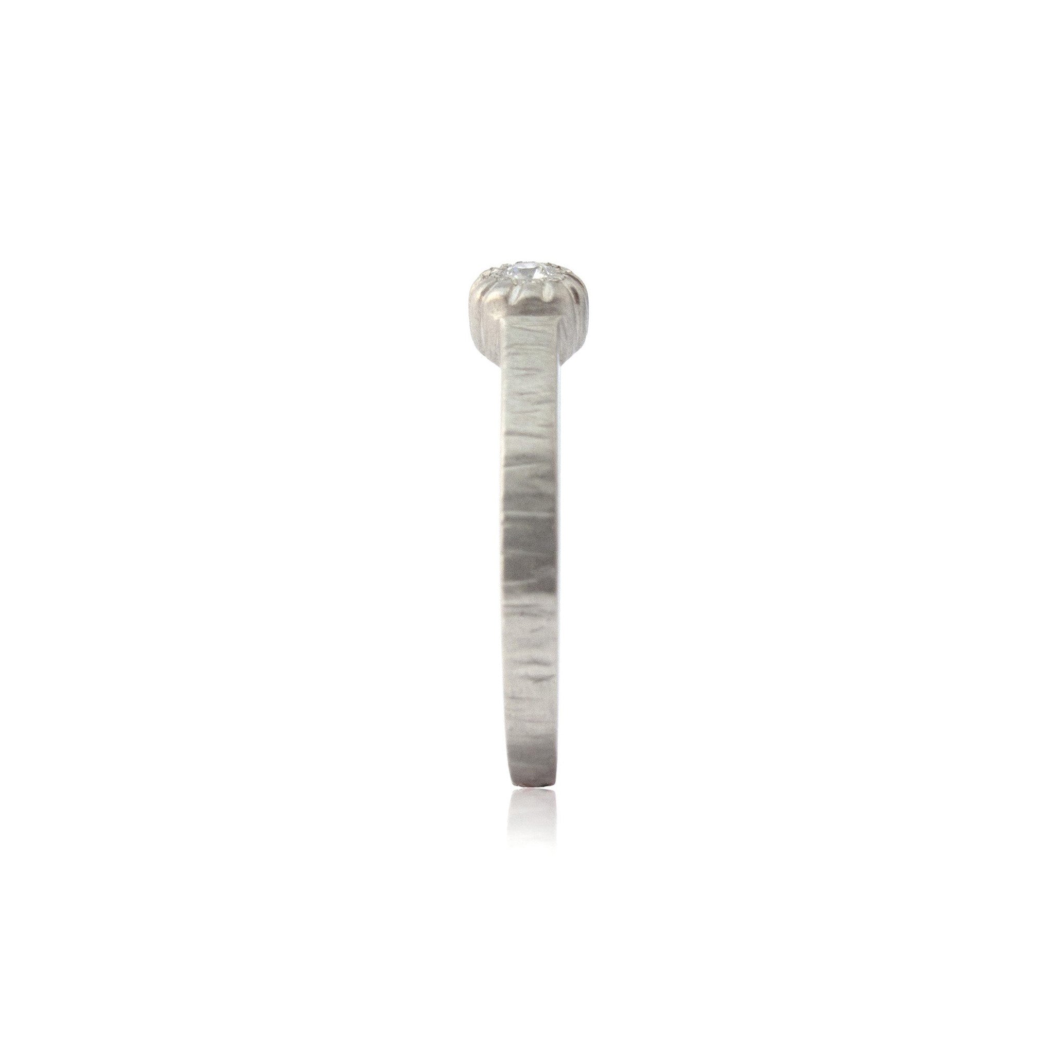 Crafted in 14KT brushed white gold, this ring features a bezel-set round brilliant-cut diamond on a flat band.