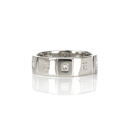 Crafted in 14KT white gold, this men’s band features six raised sections, each set with a princess-cut diamond. Alternating with hand-engraved orange blossoms in square settings.