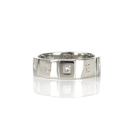 Crafted in 14KT white gold, this men’s band features six raised sections, each set with a princess-cut diamond. Alternating with hand-engraved orange blossoms in square settings. 