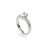 Crafted in 14KT white gold, this ring features a pear-shape diamond in a three prong setting on an orange blossom hand-engraved band set with round-cut diamonds.