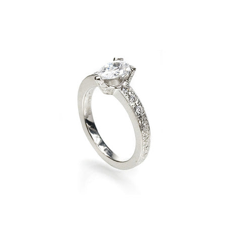 Crafted in 14KT white gold, this ring features a pear-shape diamond in a three prong setting on an orange blossom hand-engraved band set with round-cut diamonds.
