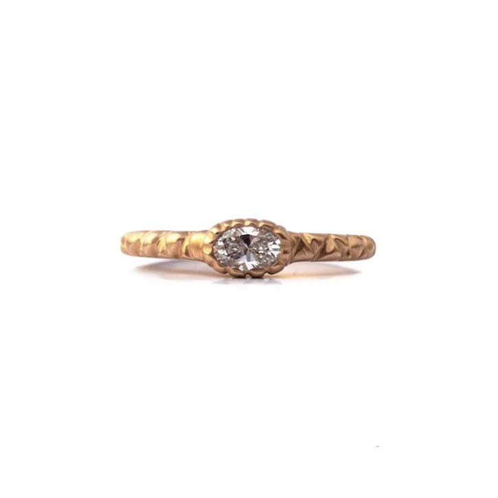 Crafted in 14KT brushed yellow gold, this ring features a bezel-set oval-cut diamond on a quilted band.