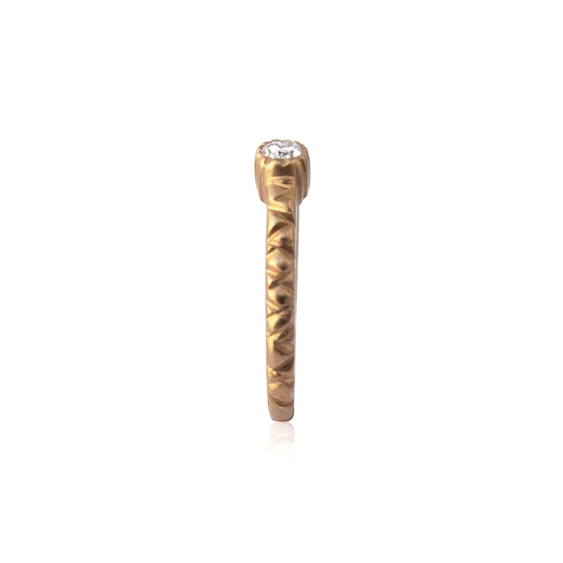 Crafted in 14KT brushed yellow gold, this ring features a bezel-set oval-cut diamond on a quilted band.