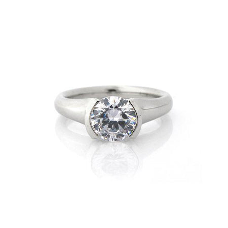 Crafted in 14KT white gold, this ring features a half-bezel set round brilliant-cut diamond with signature trademark on both sides.