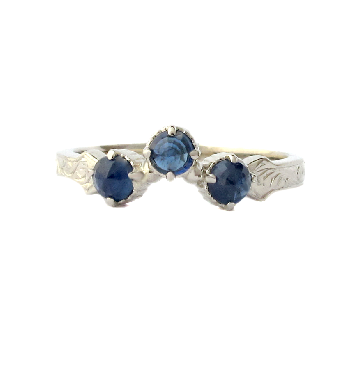 Crafted in 14KT white gold, this wrap-around ring features a curve set with 3 regal sapphires on a vintage-inspired hand engraved band.