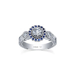 Crafted in 18KT white Canadian Certified Gold, this ring features a regal blue sapphire halo with a round brilliant-cut Canadian centre diamond on a frost-inspired hand engraved band.