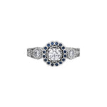 Crafted in 18KT white Canadian Certified Gold, this ring features a regal blue sapphire halo with a round brilliant-cut Canadian centre diamond on a frost-inspired hand engraved band.