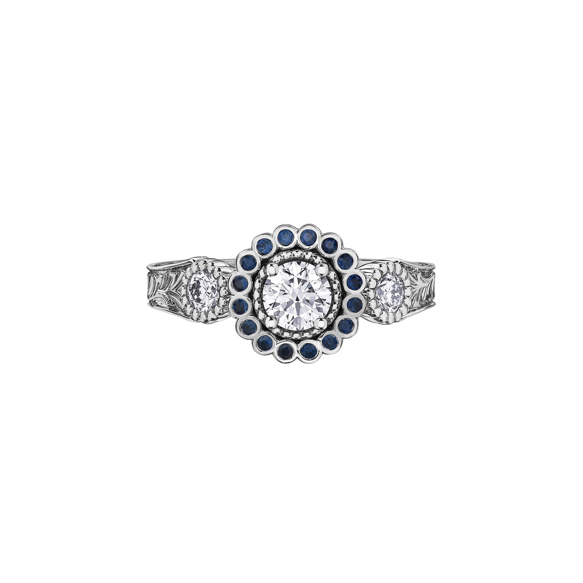 Crafted in 18KT white Canadian Certified Gold, this ring features a regal blue sapphire halo with a round brilliant-cut Canadian centre diamond on a frost-inspired hand engraved band.