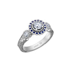 Crafted in 18KT white Canadian Certified Gold, this ring features a regal blue sapphire halo with a round brilliant-cut Canadian centre diamond on a frost-inspired hand engraved band.
