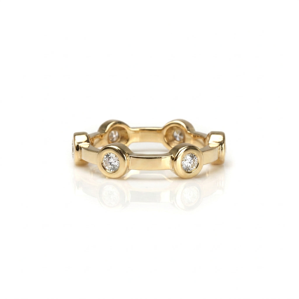 Crafted in 14KT gold, this ring features six round brilliant-cut diamonds evenly spaced apart in bezel settings on a flat band.