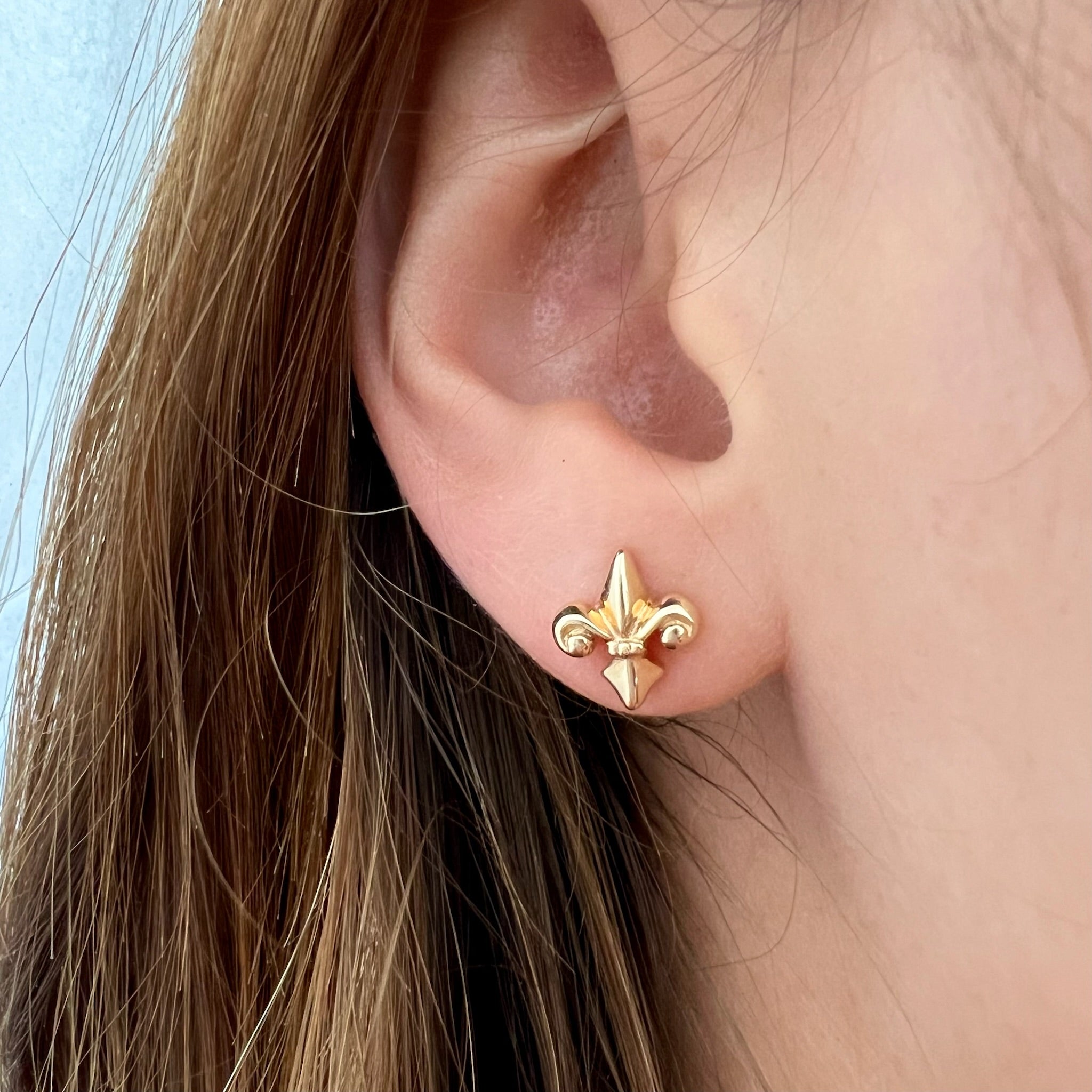 10 x 9mm fleur-de-lis stud earrings in 14K yellow, rose, or white gold, featuring an elegant royal-inspired design.