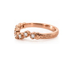 A rose gold ring with a floral cluster setting of clear round-cut gemstones and an engraved band, shown on a clean white background.