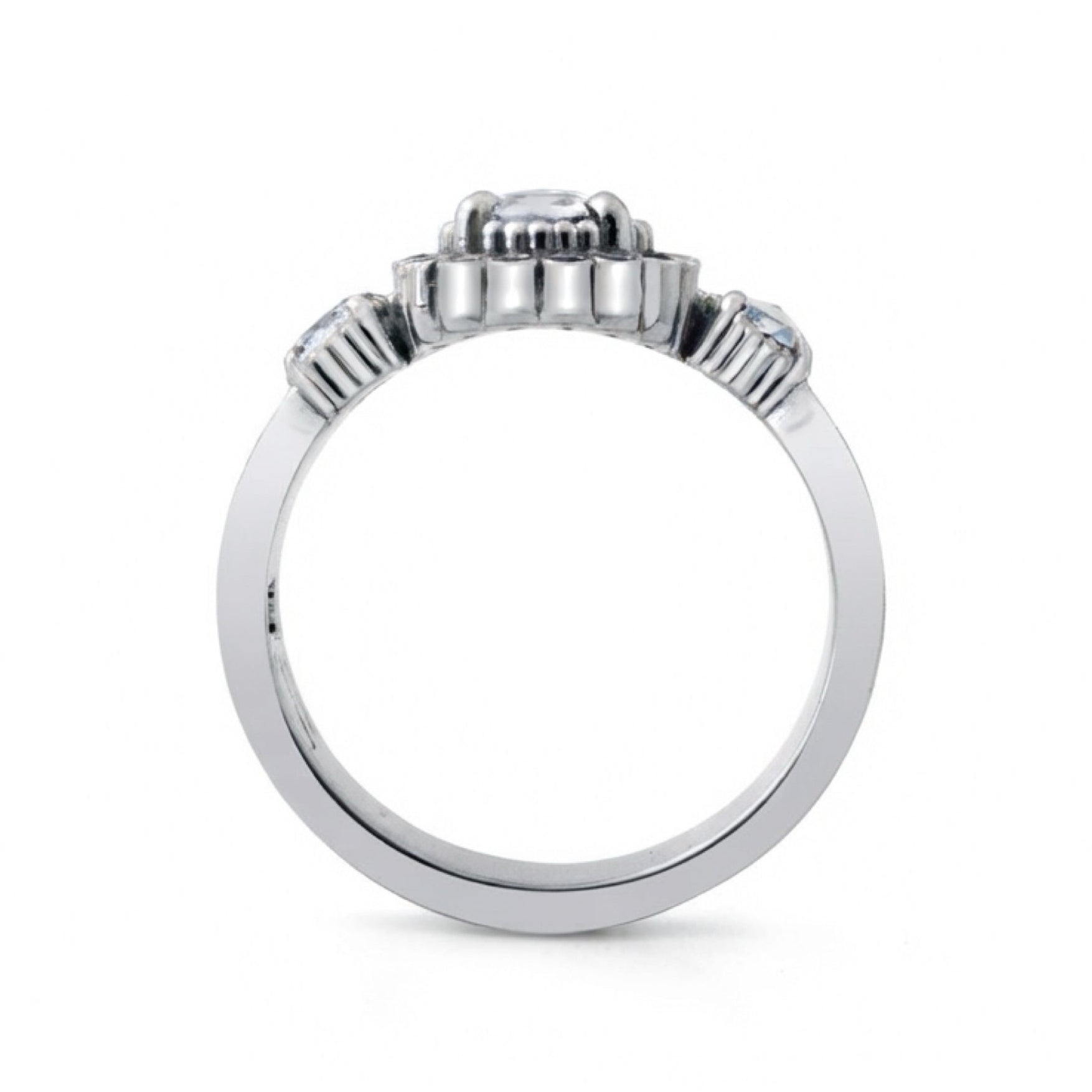 A silver-toned diamond ring with a central round-cut diamond and smaller diamonds set in decorative side clusters, shown from the back on a white background.