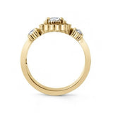 A yellow gold ring featuring a central round clear gemstone in a prong setting, with two smaller round clear gemstones on either side of the band, shown on a plain white background.