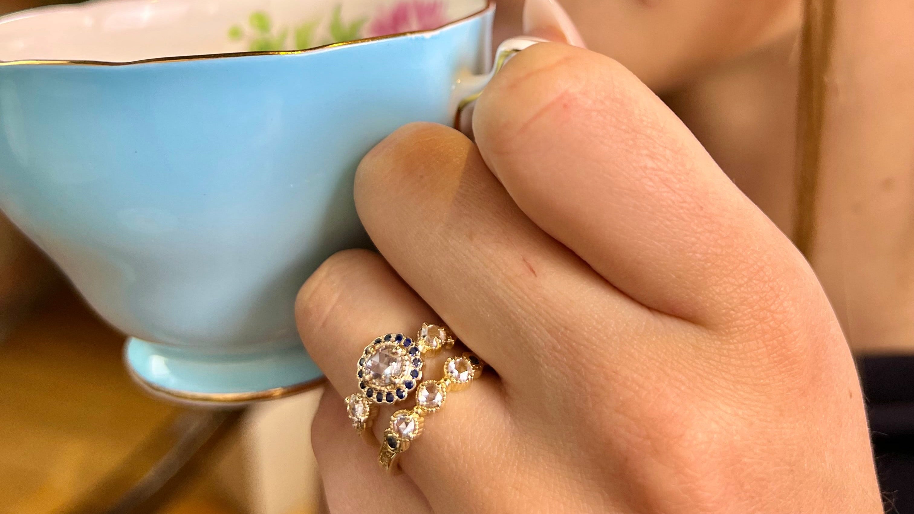 Jaqueline Ring and Alexandra Ring with hand-engraving, rose-cut diamonds and blue sapphire accent stones on woman’s hand