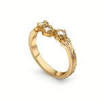 A yellow gold ring with two oval-cut clear gemstones in a prong setting, featuring an engraved pattern on the band, shown on a white background.