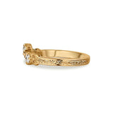 A yellow gold ring with an ornate filigree band and a small cluster of clear gemstones at the setting, shown on a plain white background.