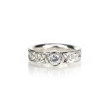 Crafted in 14KT gold, this comfort-fit engagement ring is set with a round brilliant-cut diamond between two smaller round brilliant-cut diamonds on a paisley hand-engraved band. 