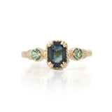 A vintage-style ring featuring a large emerald cut sapphire centerpiece with two round alexandrite accents, set in hand-engraved 14KT yellow gold.