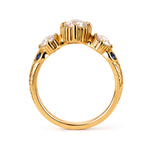 A gold ring featuring three round clear gemstones in a row of prong settings, accented by small round blue sapphires on the shoulders, shown against a plain white background.