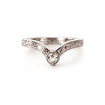 A silver V-shaped solitaire ring with an ornate filigree band and a clear round-cut gemstone, photographed on a seamless white background.