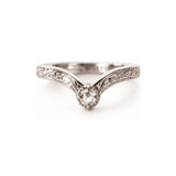 A silver V-shaped solitaire ring with an ornate filigree band and a clear round-cut gemstone, photographed on a seamless white background.