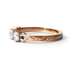 Crafted in 14KT yellow gold, this ring features 3 round brilliant-cut diamonds in a row, with a blue sapphire on either side on a vintage-inspired hand engraved band.