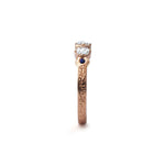 Crafted in 14KT rose gold, this ring features 3 round brilliant-cut diamonds in a row, with a blue sapphire on either side on a vintage-inspired hand engraved band.