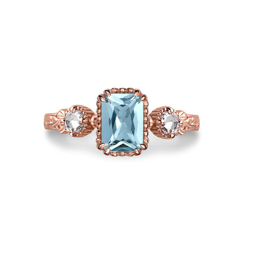 Crafted in 14KT rose gold, this ring features an aquamarine between two round brilliant-cut diamonds on a vintage-inspired hand engraved band.