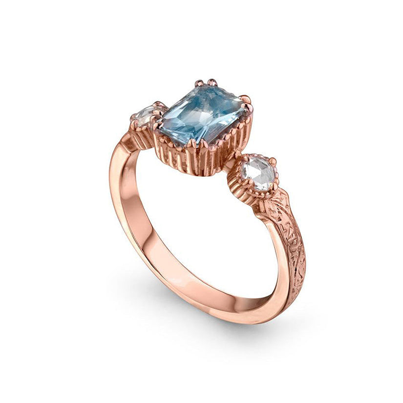 Crafted in 14KT rose gold, this ring features an aquamarine between two round brilliant-cut diamonds on a vintage-inspired hand engraved band.