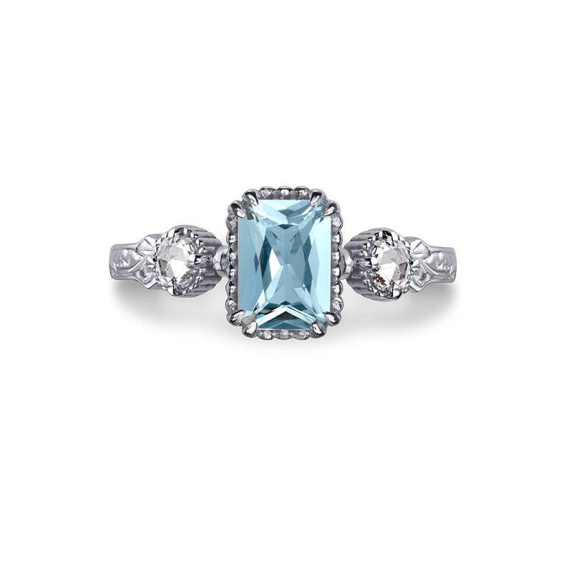 Crafted in 14KT white gold, this ring features an aquamarine between two round brilliant-cut diamonds on a vintage-inspired hand engraved band.