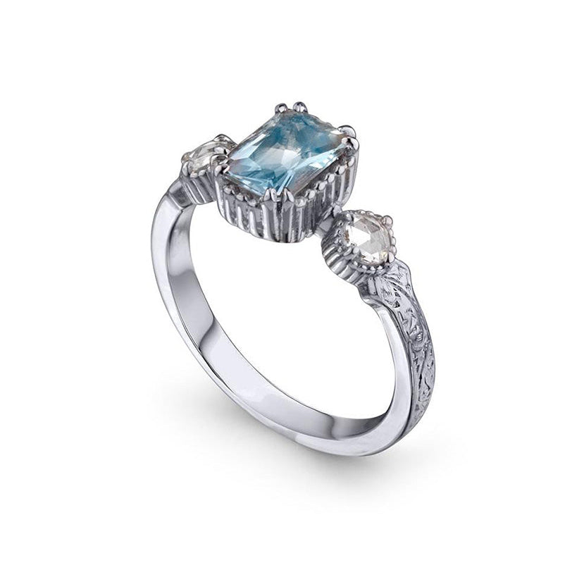 Crafted in 14KT white gold, this ring features an aquamarine between two round brilliant-cut diamonds on a vintage-inspired hand engraved band.