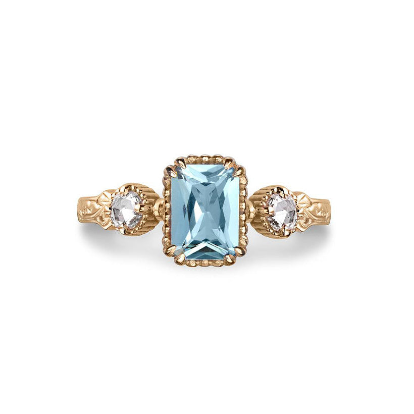 Crafted in 14KT yellow gold, this ring features an aquamarine between two round brilliant-cut diamonds on a vintage-inspired hand engraved band.