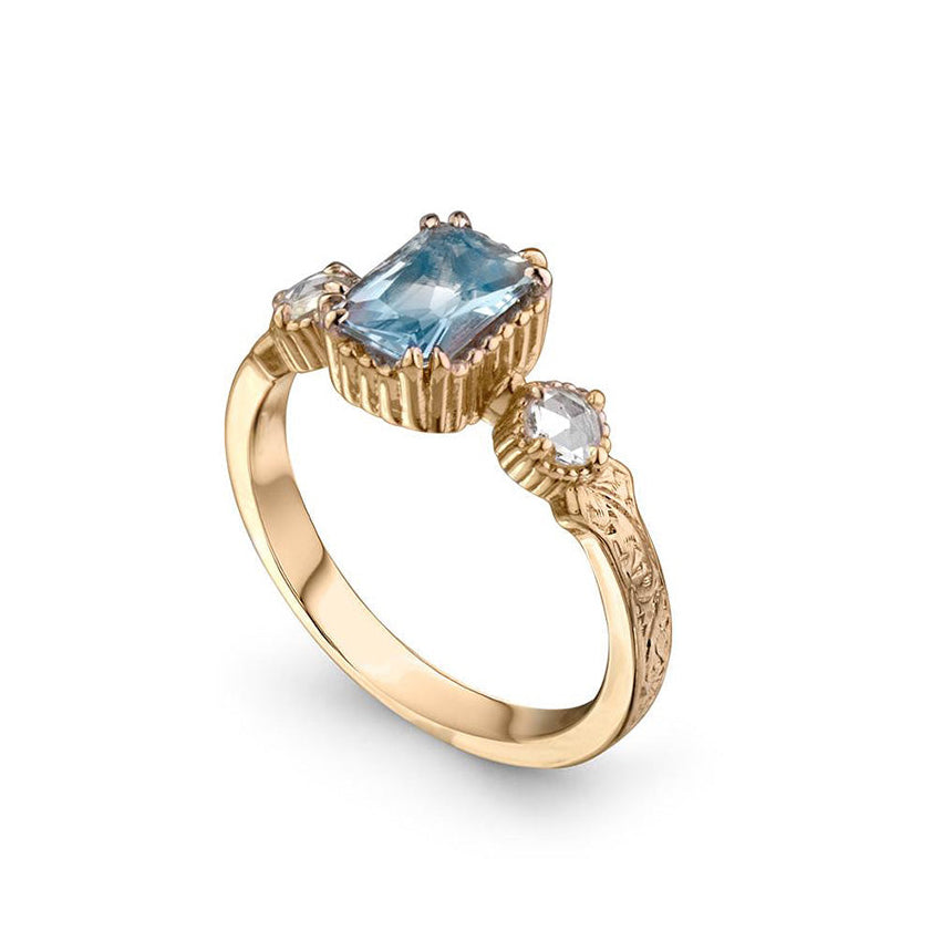 Crafted in 14KT yellow gold, this ring features an aquamarine between two round brilliant-cut diamonds on a vintage-inspired hand engraved band.