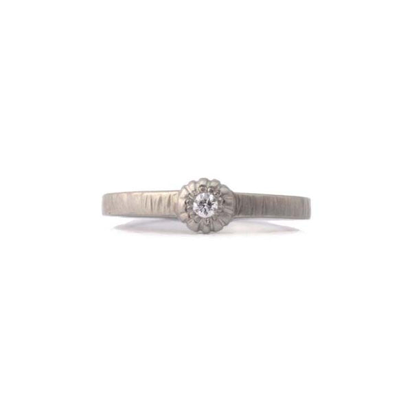 Crafted in 14KT brushed white gold, this ring features a bezel-set round brilliant-cut diamond on a flat band. 