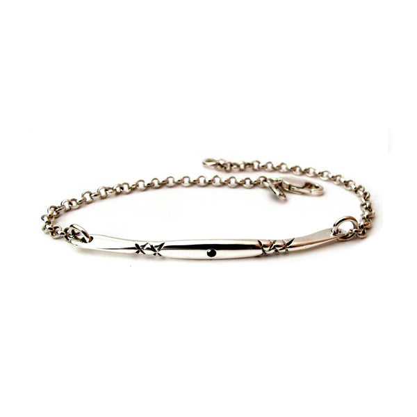 Crafted in 14KT white gold, this bracelet has a bar set with a black diamond and x-designs. 