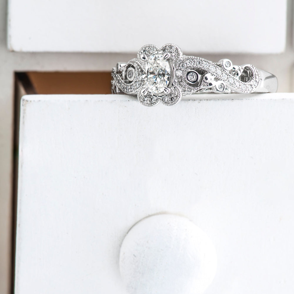 18kt gold engagement ring with oval-cut Canadian diamond, diamond side stones, and intricate rose vine detailing, 0.45 TDW.