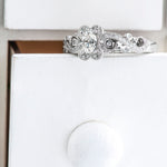 18kt gold engagement ring with oval-cut Canadian diamond, diamond side stones, and intricate rose vine detailing, 0.45 TDW.