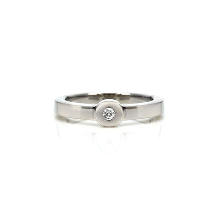 Crafted in 14KT white gold, this ring features a bezel set round brilliant-cut diamond and a flat band.