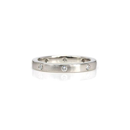 Crafted in 14KT white gold, this ring features eight round brilliant-cut diamonds evenly spaced apart on a flat band.