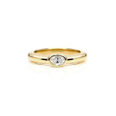 Crafted in 14KT yellow gold, this ring features a bezel set oval-cut diamond.