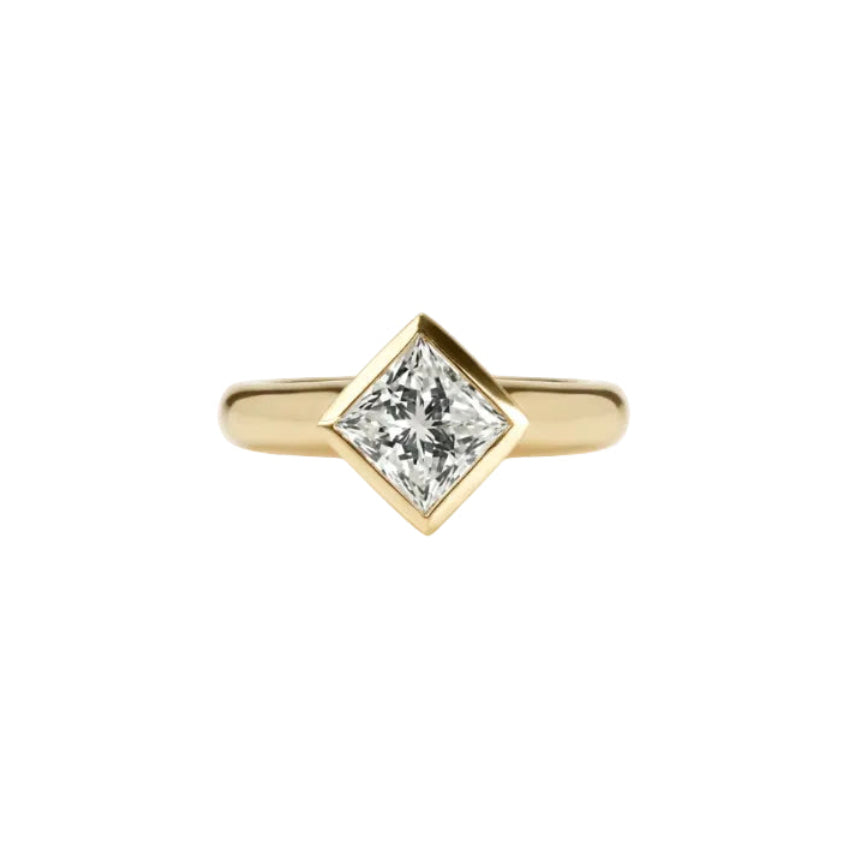 Crafted in 14KT gold, this engagement ring features a bezel set princess-cut diamond. 