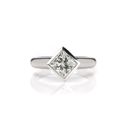 Crafted in 14KT white gold, this ring features a bezel set princess-cut diamond. 