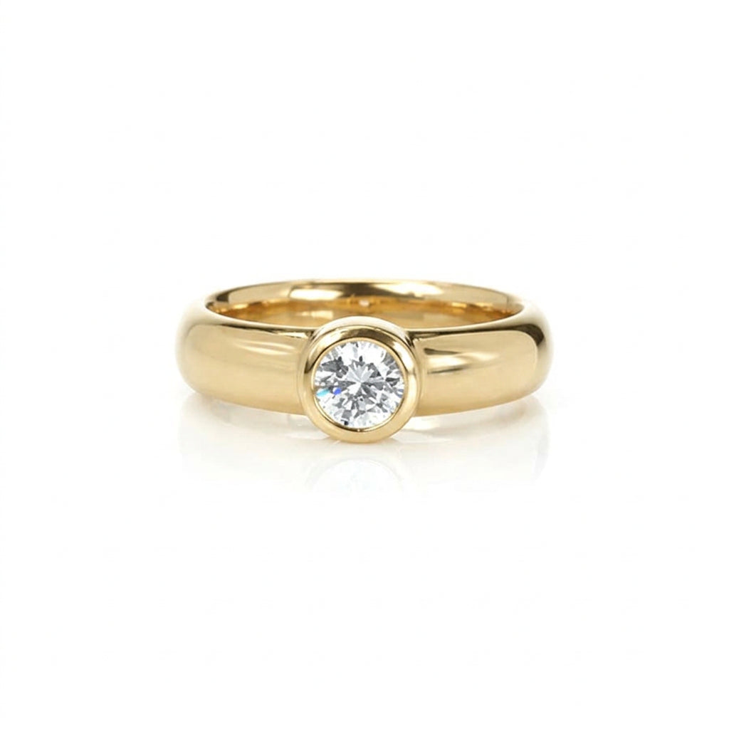 Crafted in 14KT gold, this engagement ring features a bezel set round brilliant-cut diamond. 