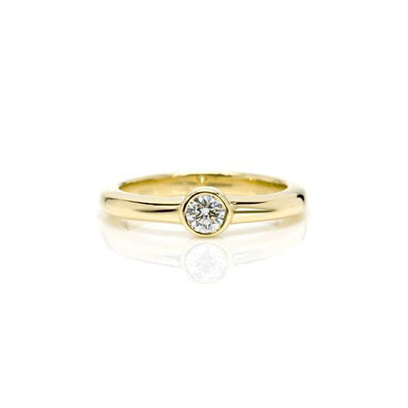 Crafted in 14KT yellow gold, this ring features a bezel set round brilliant-cut diamond.