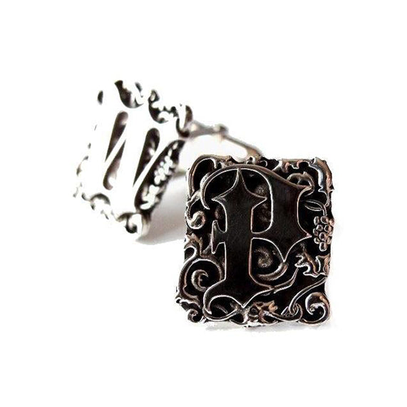Crafted in sterling silver, these cufflinks feature goth style letters entwined in foliage.