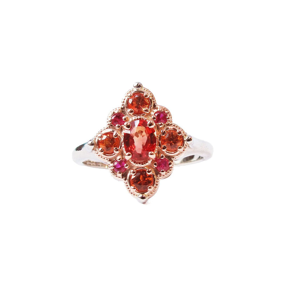 Crafted in 14KT rose and white gold, this ring features round and oval-cut orange and red sapphires set in a diamond shape. 
