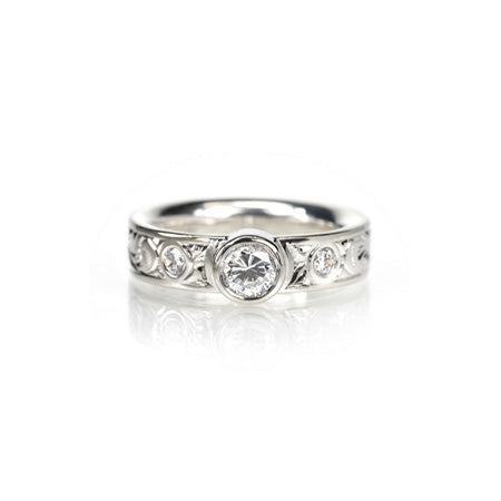 Crafted in 14KT white gold, this comfort-fit ring is set with a round brilliant-cut diamond between two smaller round brilliant-cut diamonds on a paisley hand-engraved band. 